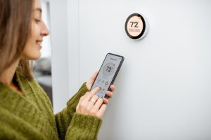 person-setting-their-smart-thermostat-with-their-phone